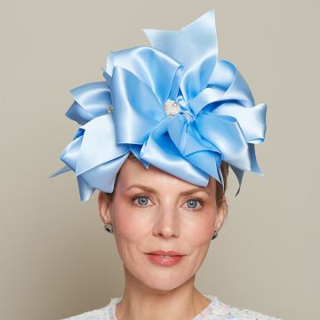 A V V Chapeaux headdress made from metres of Cornflower Blue double faced satin folded into bows stacked upon one another, each centred with a Pearl and Diamante beaded brooch. 
