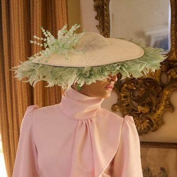 A V V Chapeaux Clotted Cream sinamay saucer hat with Pale Slate goose feather trim, hand-painted Lily of the Valley and pearl detail.
